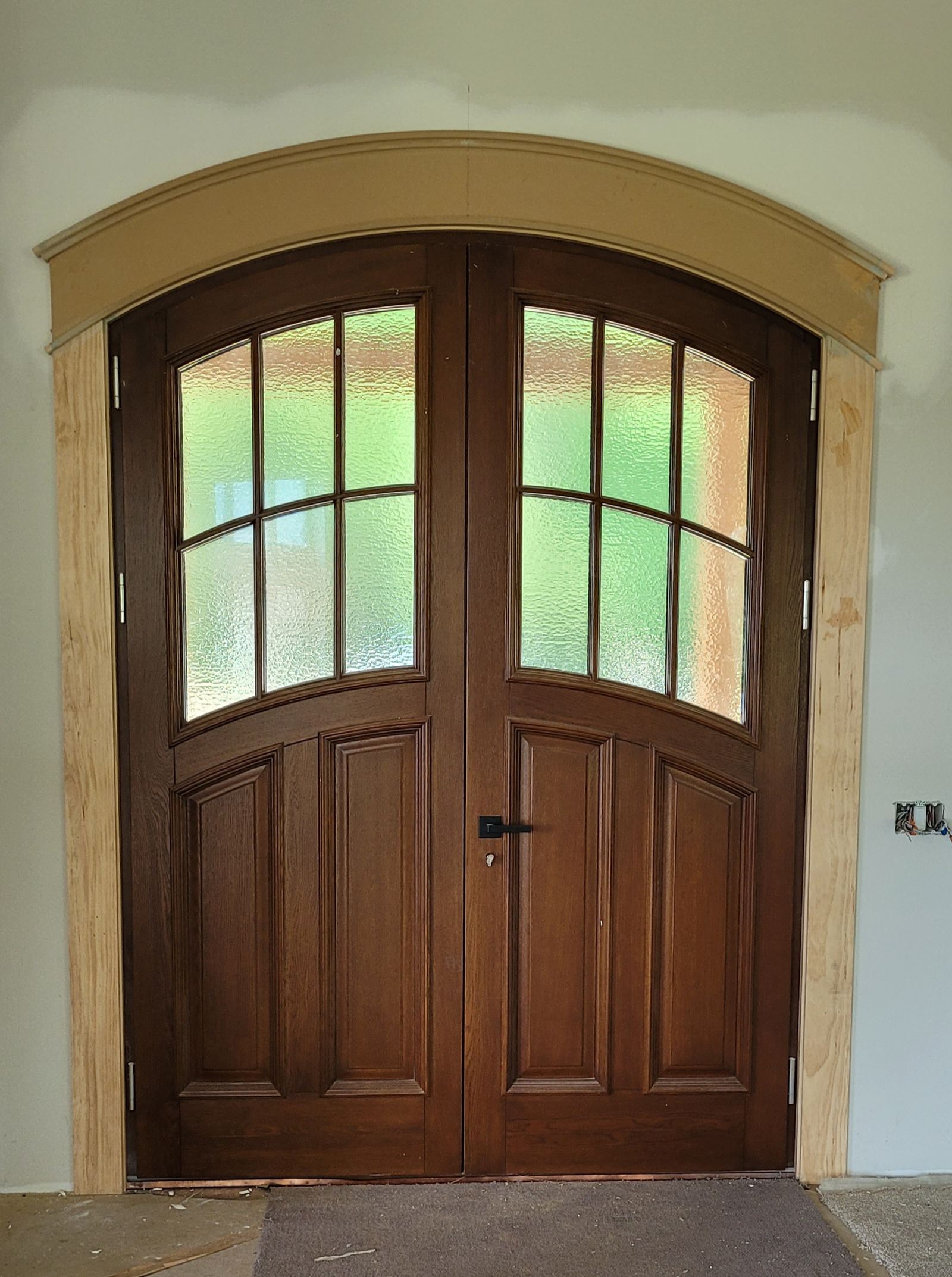 Arched mahogany entry door with custom casing