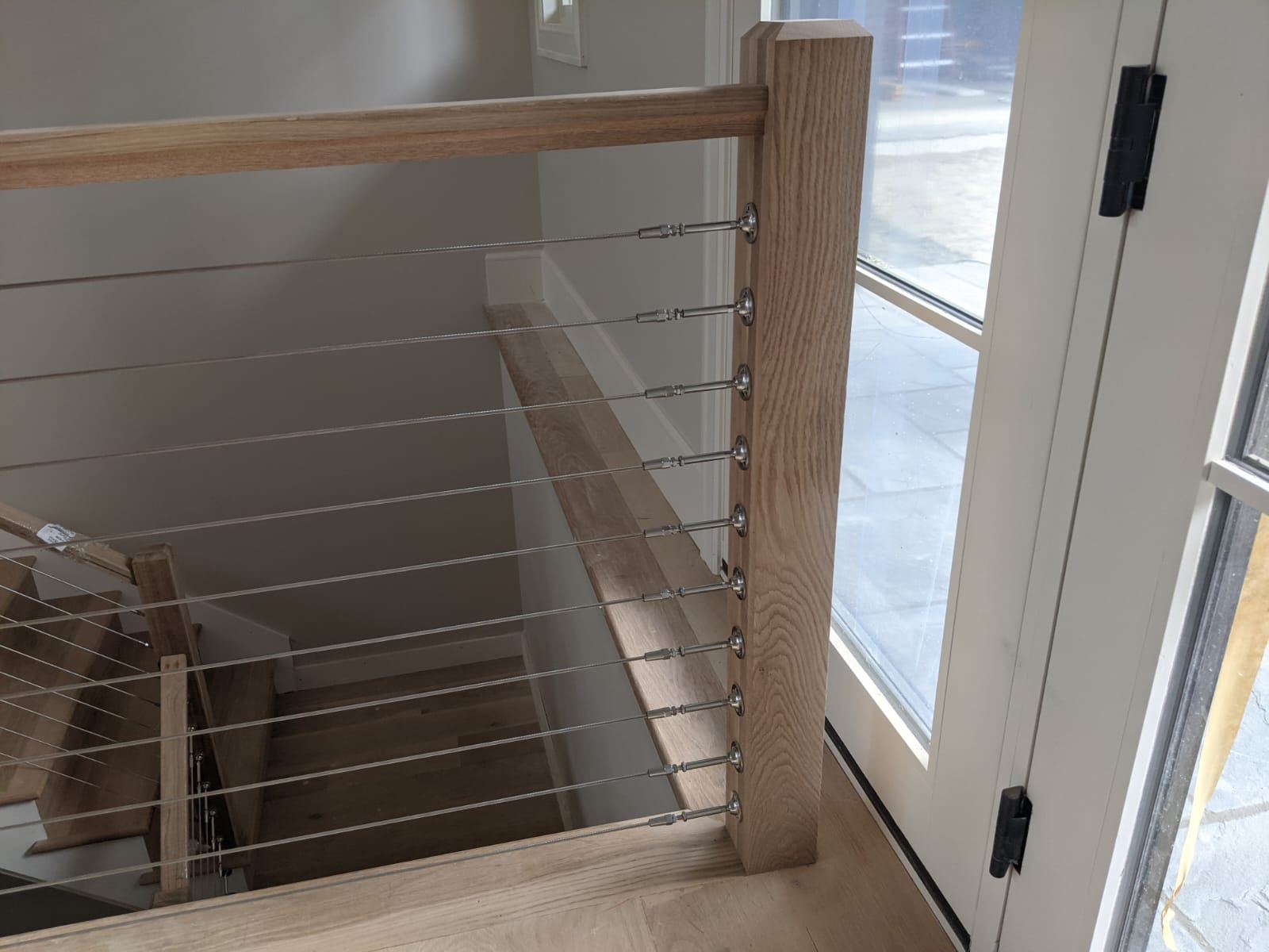 White oak open-tread stair with stainless cable railing seen from the living space