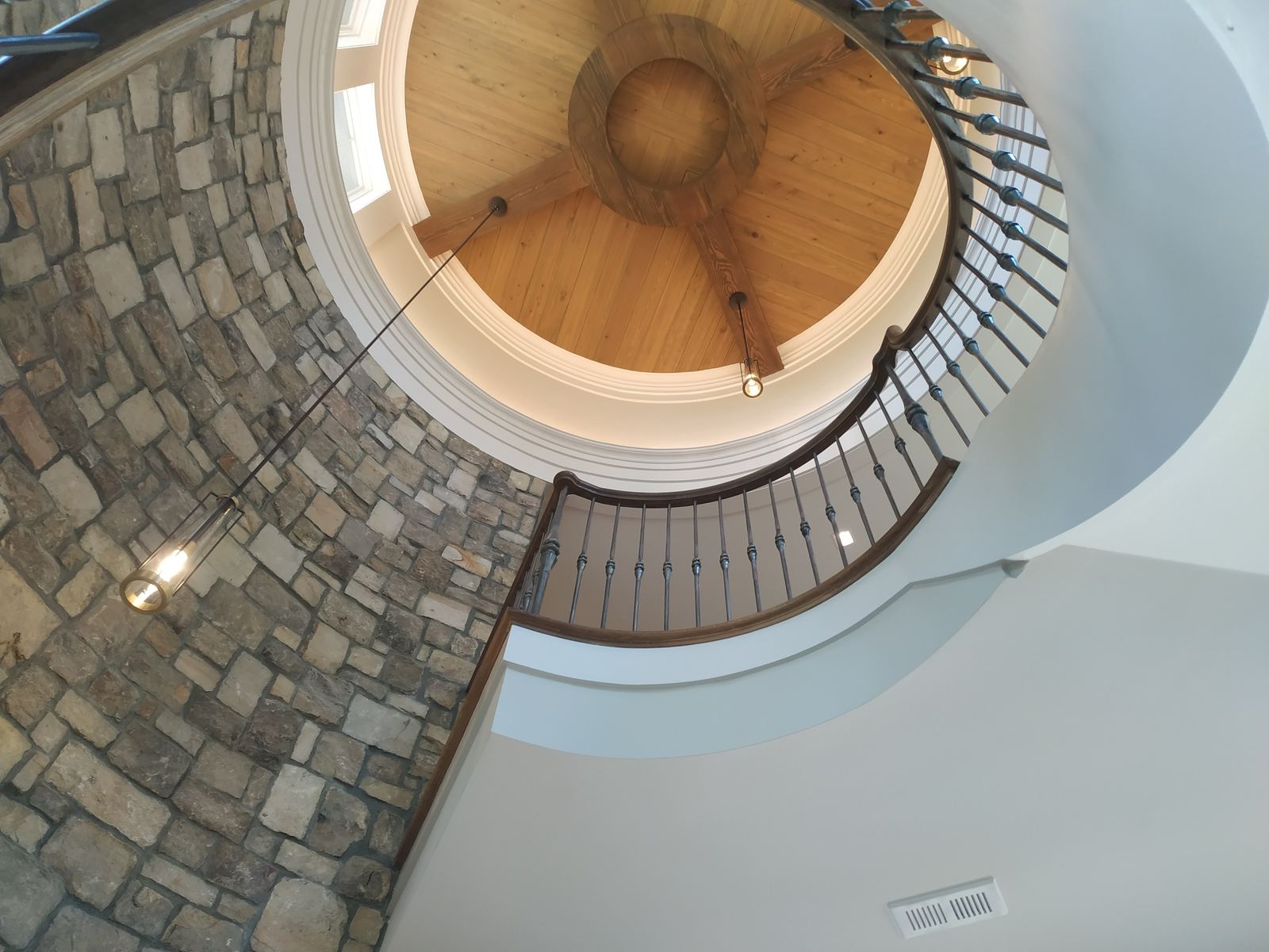 Curved wood railing following a stone stair beneath a domed timber ceiling
