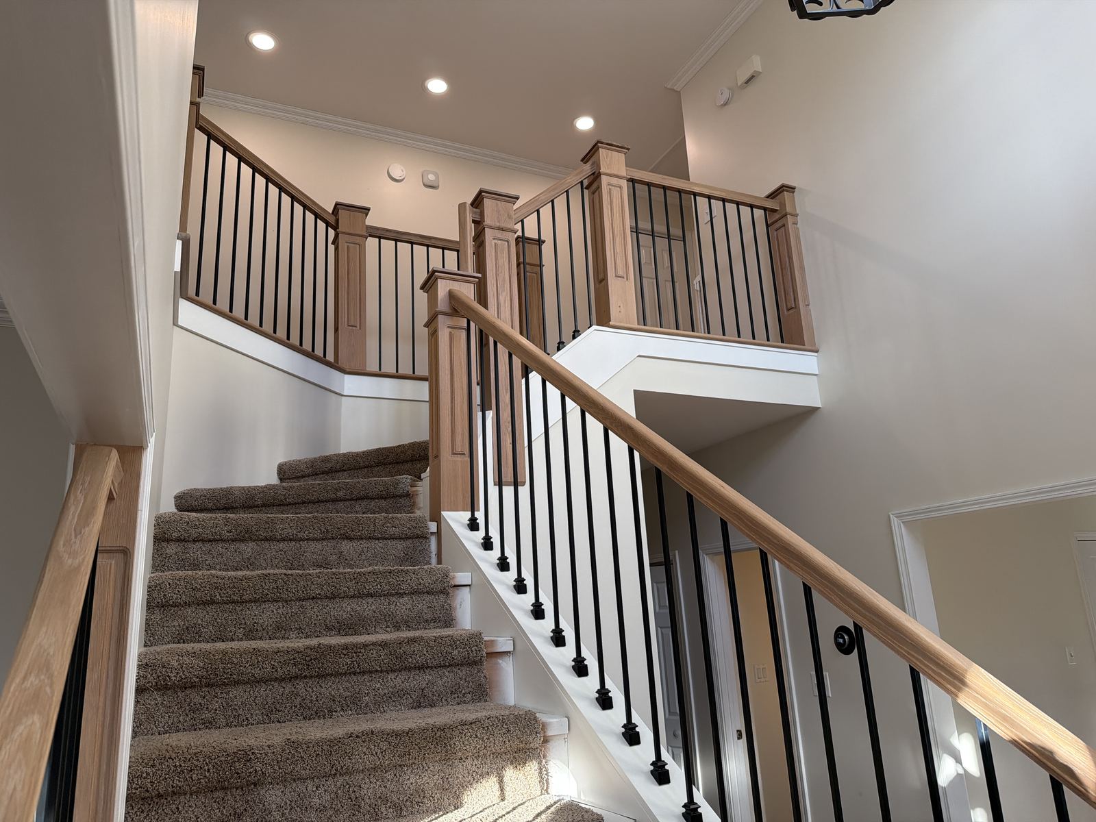 Curved oak staircase with iron balusters in an entry foyer